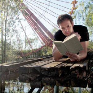 Bas Böttcher liegt auf Holzssteg mit einem Buch in der Hand