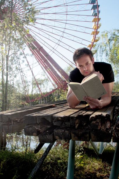 Bas Böttcher liegt auf Holzssteg mit einem Buch in der Hand