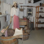 Historische Waschküche mit verschiedenen Geräten und einer Kleiderpuppe